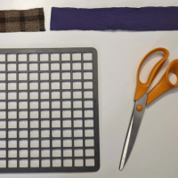 Photo of a black rubber mat, scissors and strips of fabric