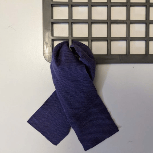 Photo of a strip of fabric fed through the rubber mat and being tied