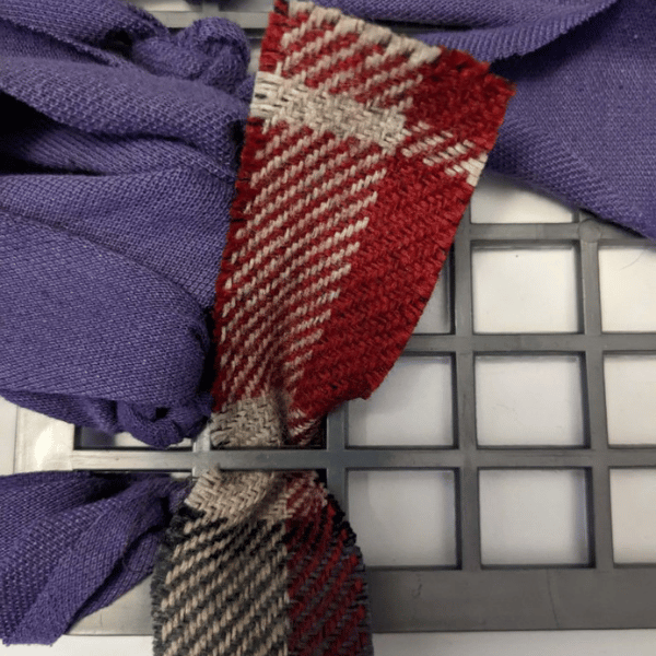 Photo of a strip of fabric fed through the rubber mat and being tied