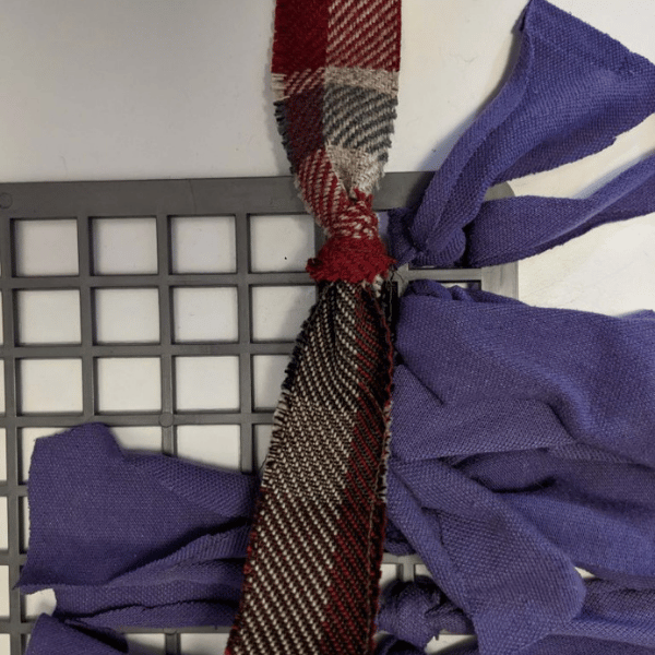 Photo of a strip of fabric fed through the rubber mat and being tied