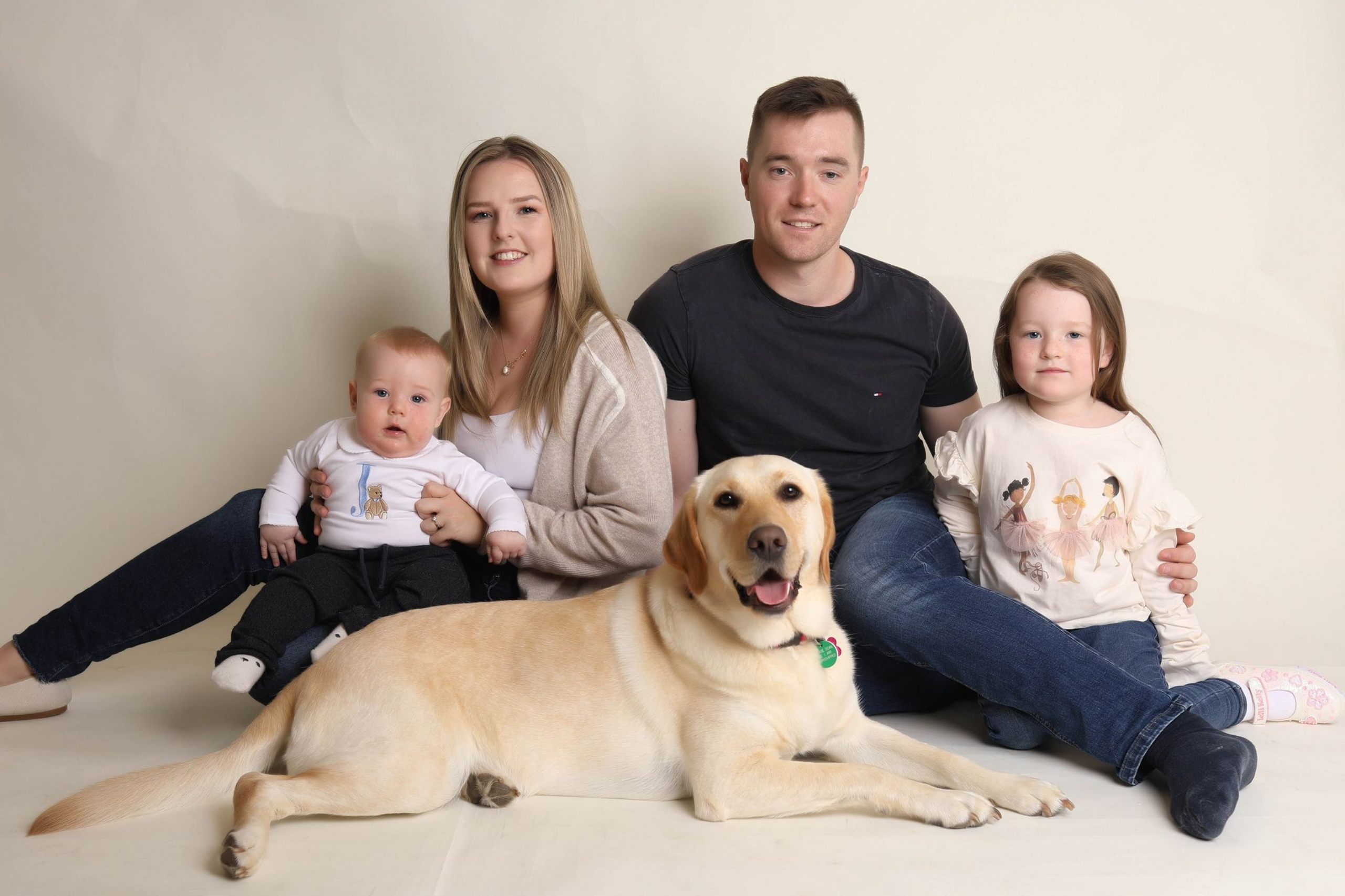Photo of family mum dad two children and a yellow labrador at the front