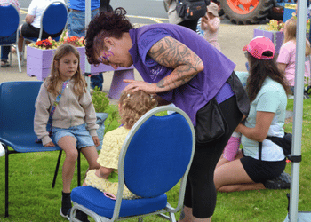 Photo of lady painting boys face with face paint