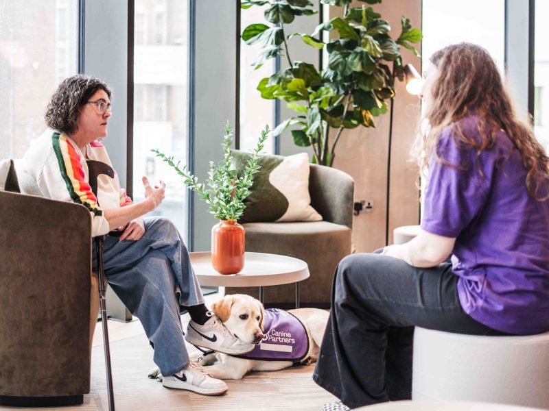 Photo of Canine Partners staff talking to a partner with their assistance dog lying on the floor
